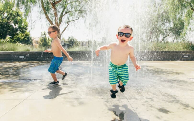 Two little boys playing in the water at a splash pad at New Haven in Ontario Ranch CA 810x506